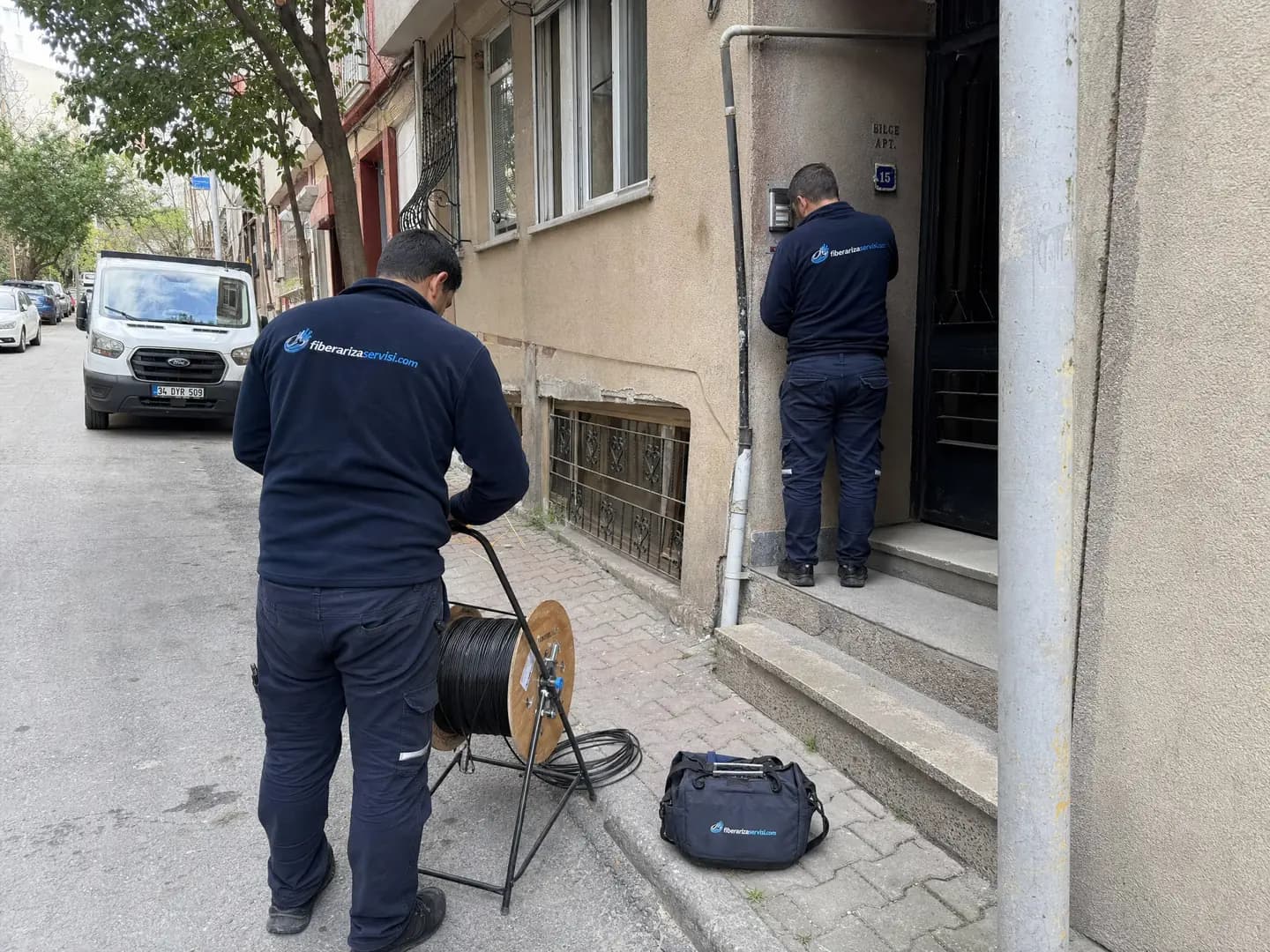 Apartman girişinde fiber kablo çekimi için çalışan teknik ekip