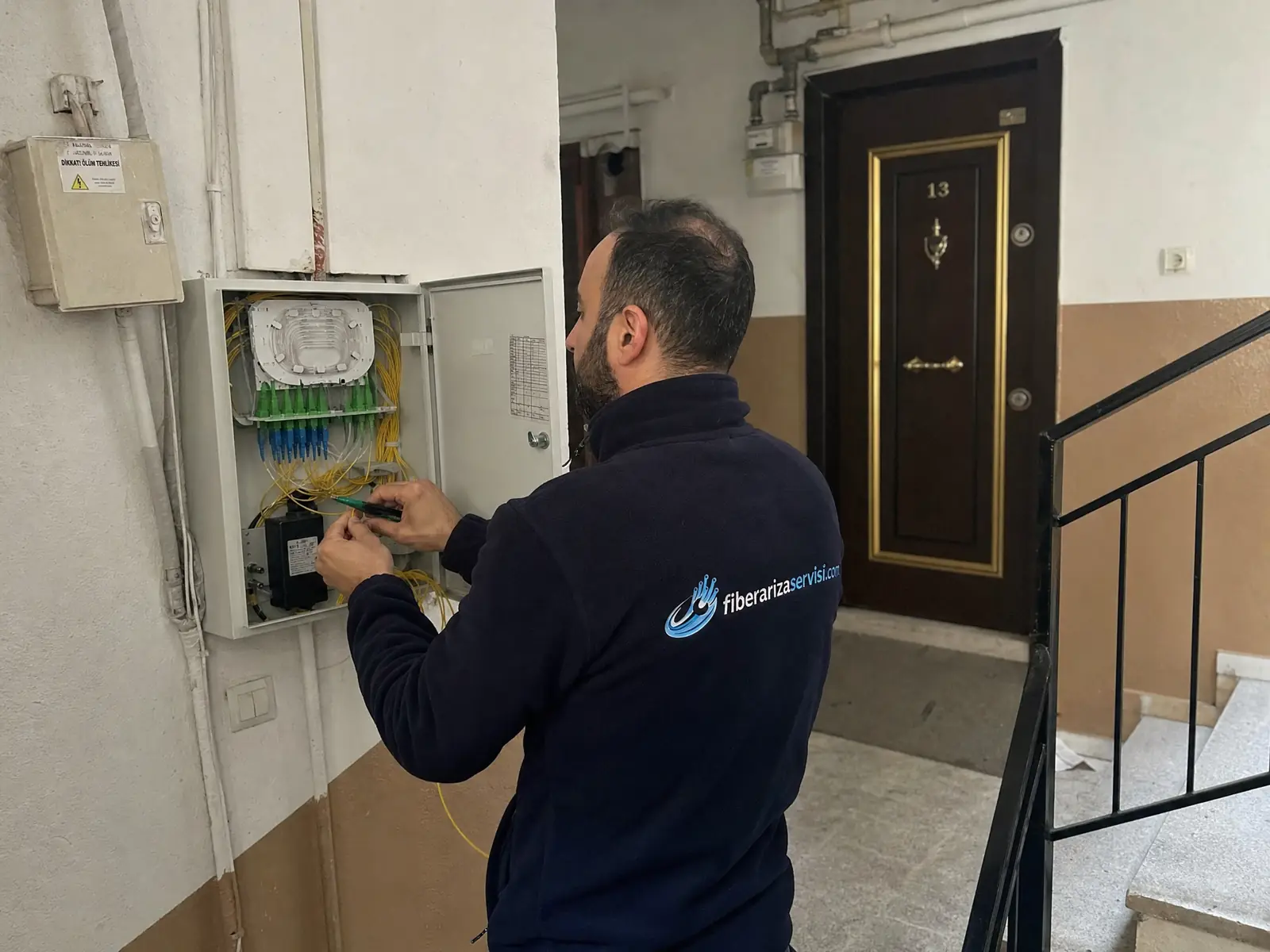 Apartman içindeki fiber dağıtım kutusunda bağlantı kontrolü yapan teknisyen